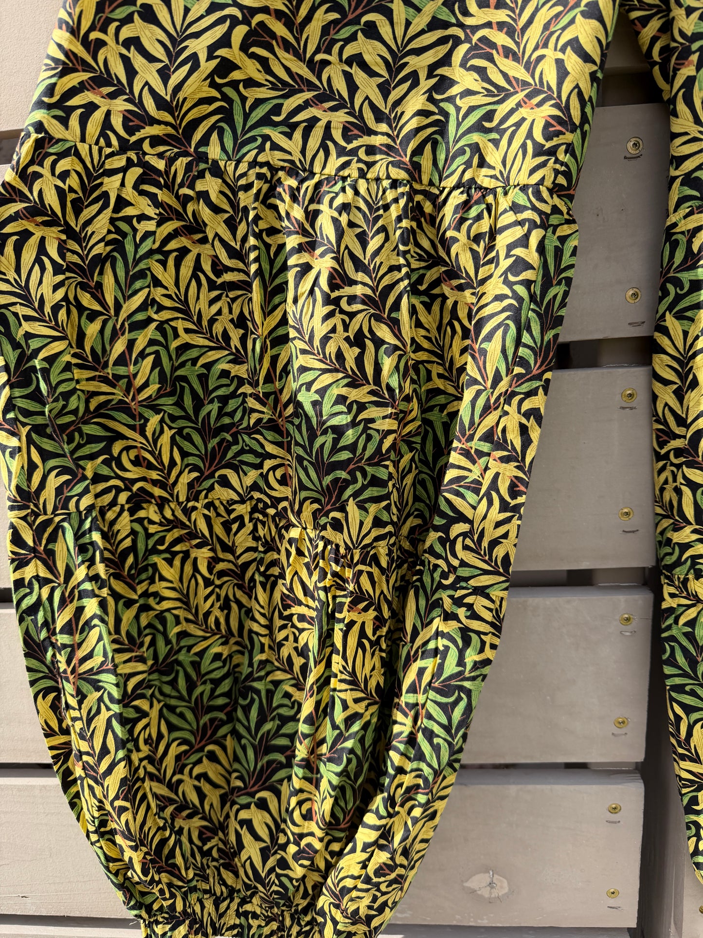 Green and yellow patterned fabric draped over a wooden surface with metal lockers in the background.
