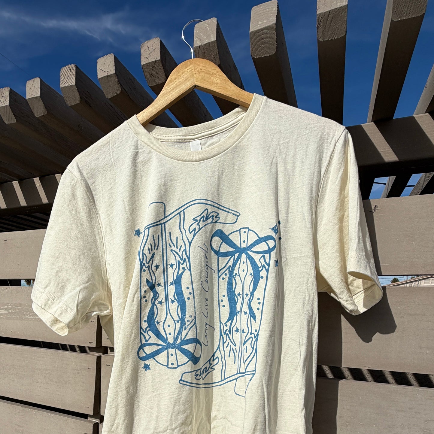 White t-shirt with blue graphic design on a wooden surface