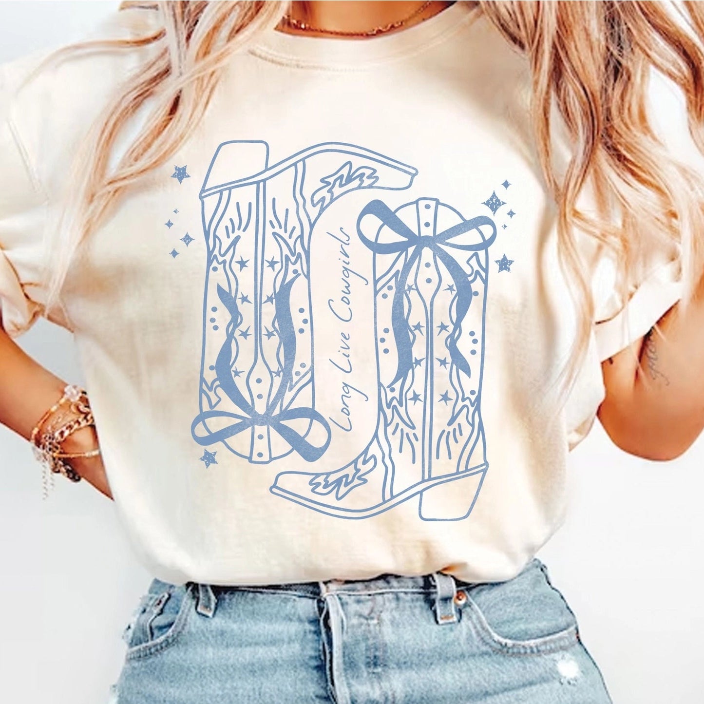 Person wearing a white t-shirt with blue graphic design and high-waisted jeans on a plain background