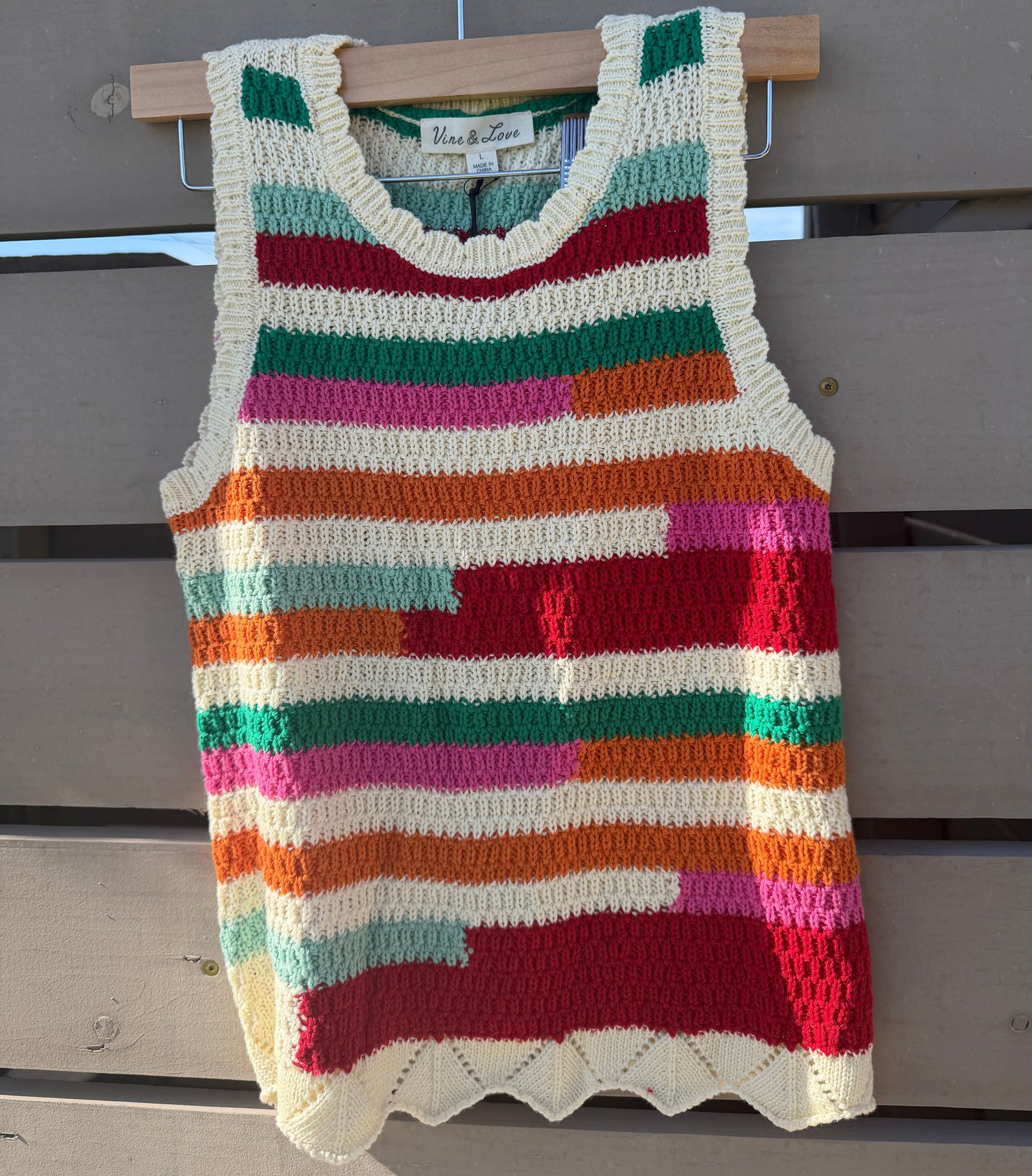 Colorful striped crochet tank top hanging on a wooden surface