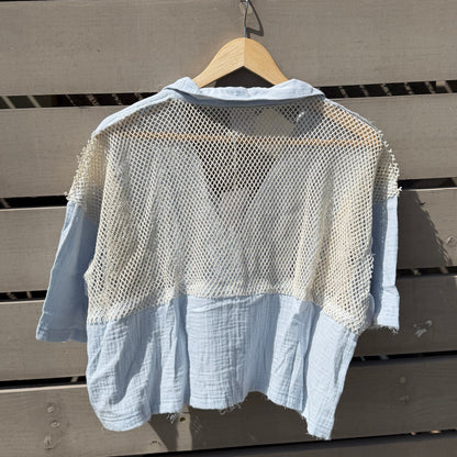 Light blue shirt on a wooden hanger against a wooden wall