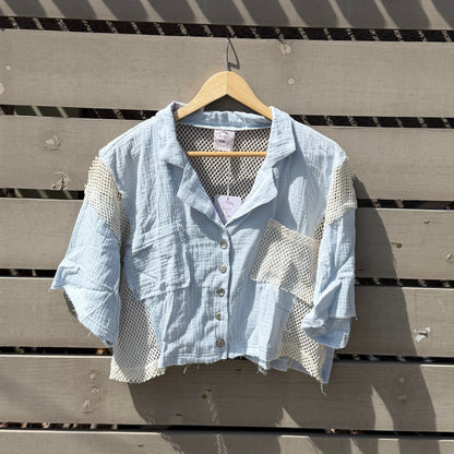Light blue shirt on a hanger against a wooden wall