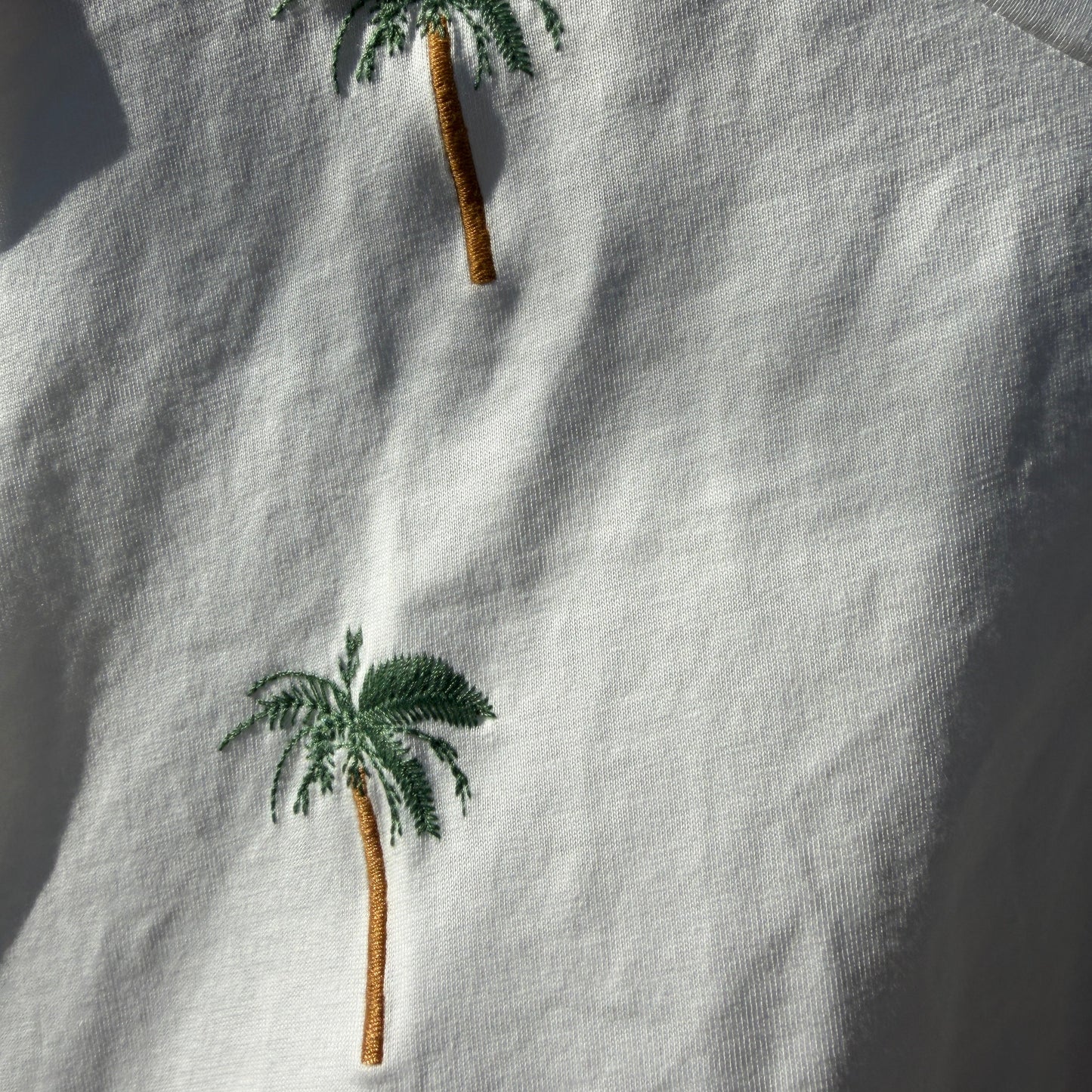 Embroidered palm trees on a light fabric background