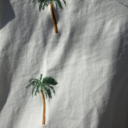 Embroidered palm trees on a light fabric background
