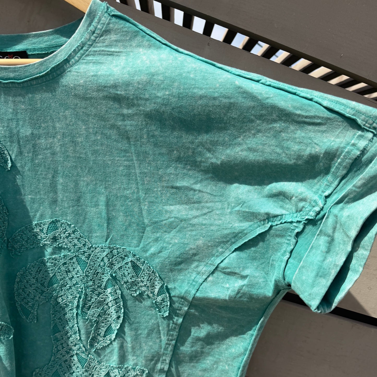 Green tank top with a logo on a wooden surface