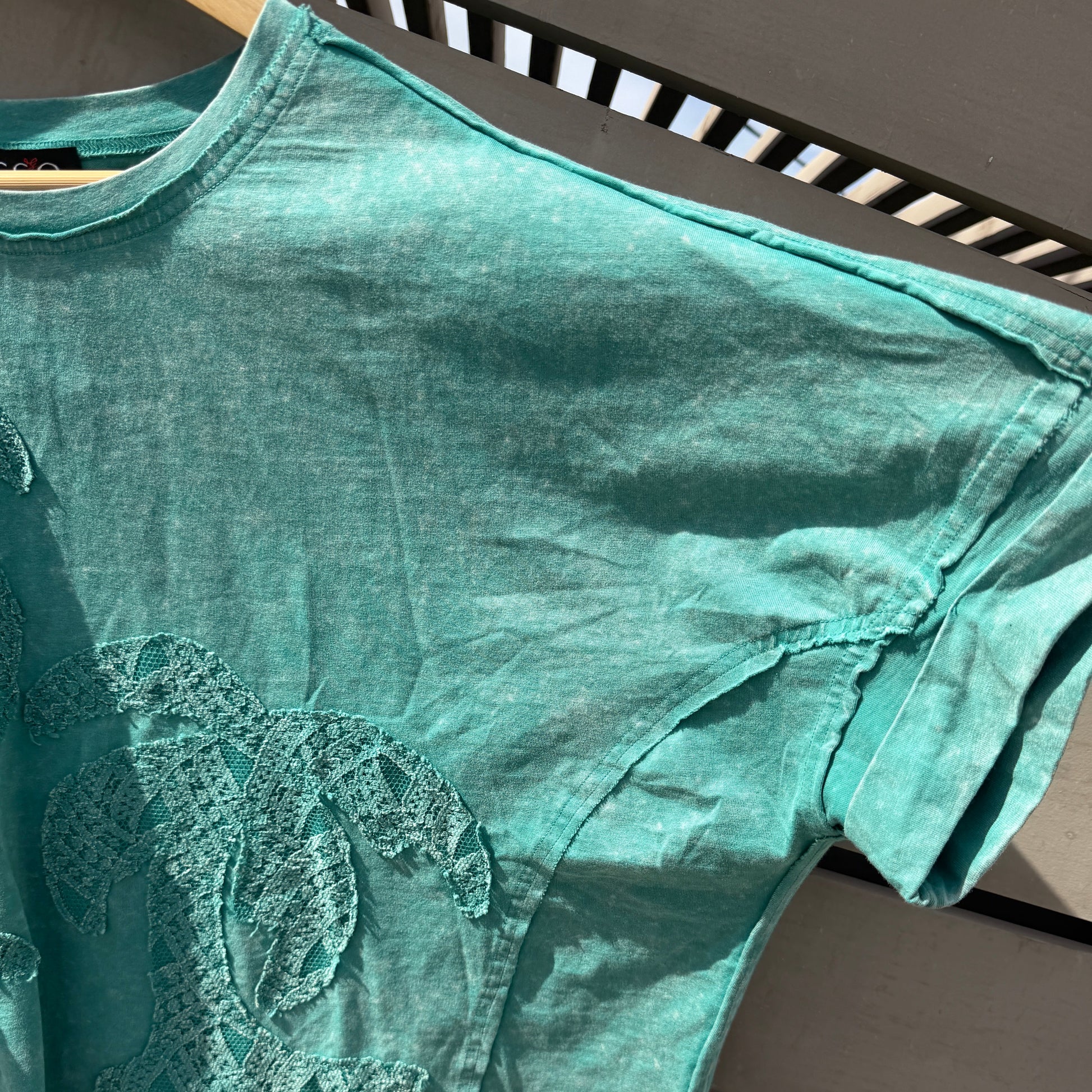 Green tank top with a logo on a wooden surface
