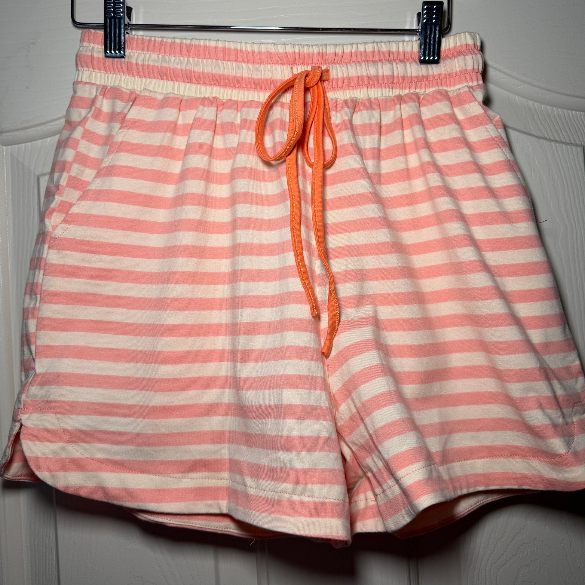 Pink and white striped drawstring bag on a hanger against a neutral background