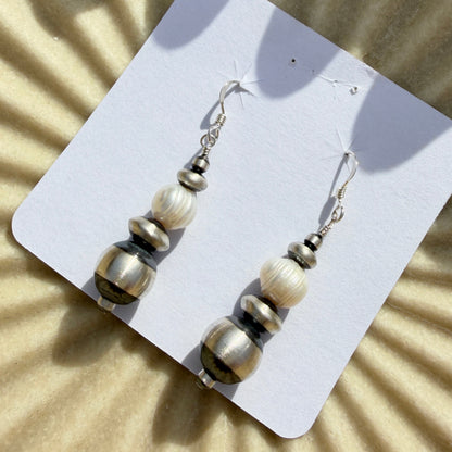 Pair of beaded earrings on a white card with a sunburst pattern in the background
