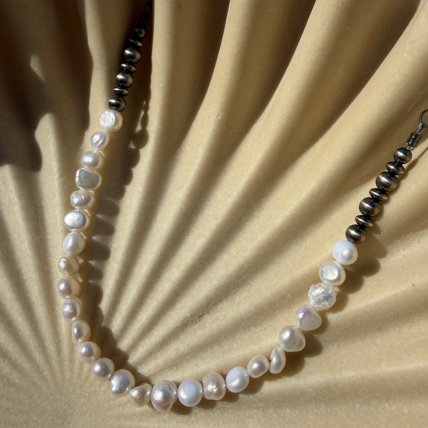 Pearl necklace on a textured beige surface