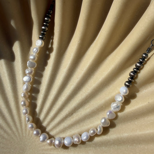 Pearl necklace on a textured beige surface