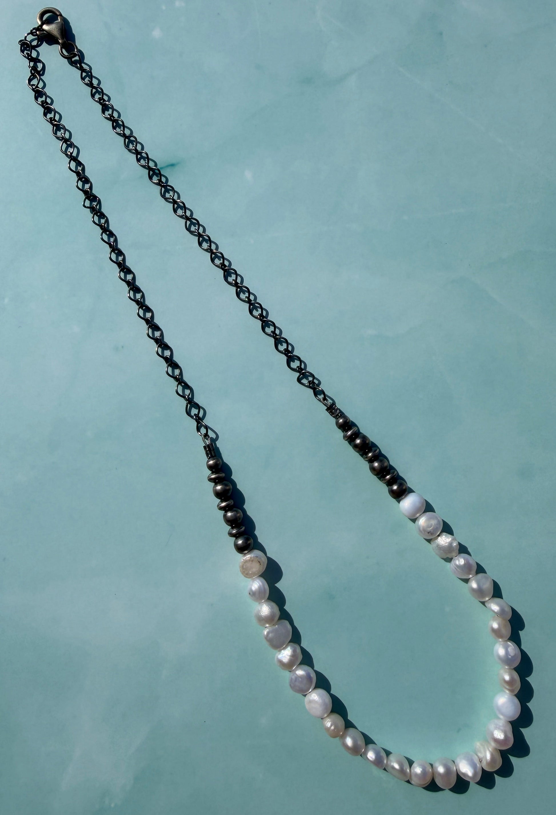 Necklace with white pearls on a light blue background