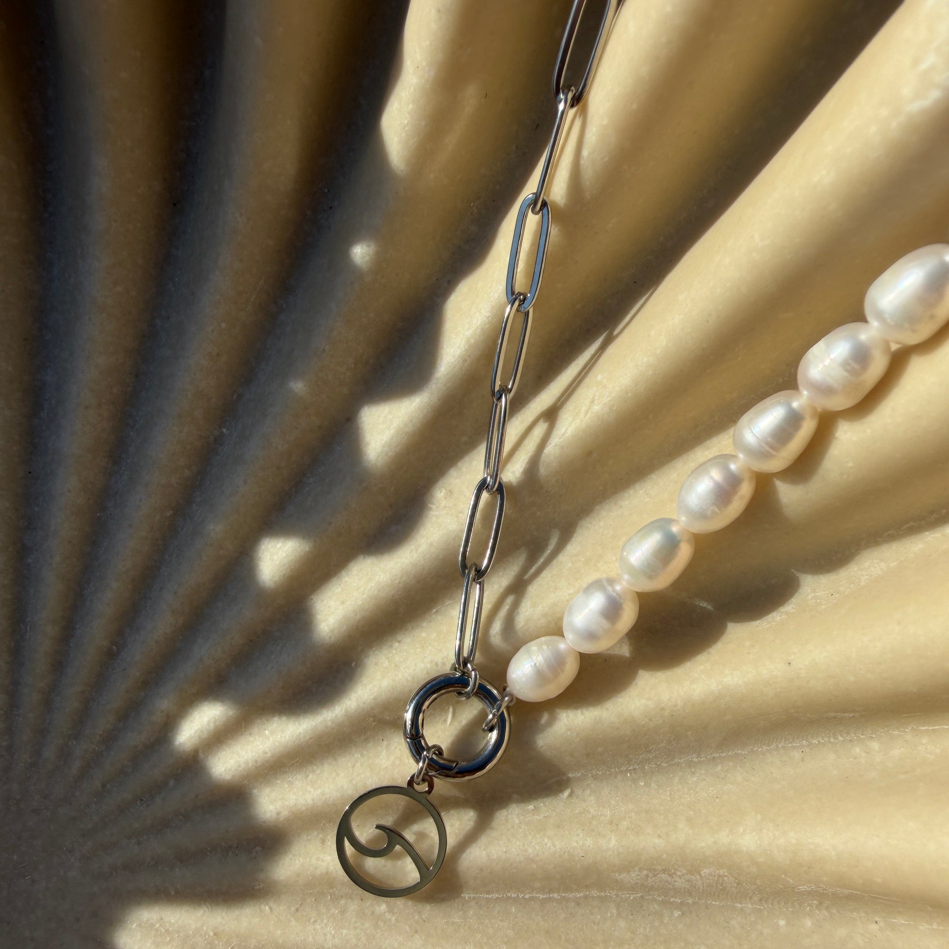 Pearl necklace with silver clasp on a textured beige surface