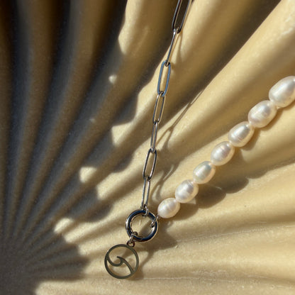 Pearl necklace with silver clasp on a textured beige surface