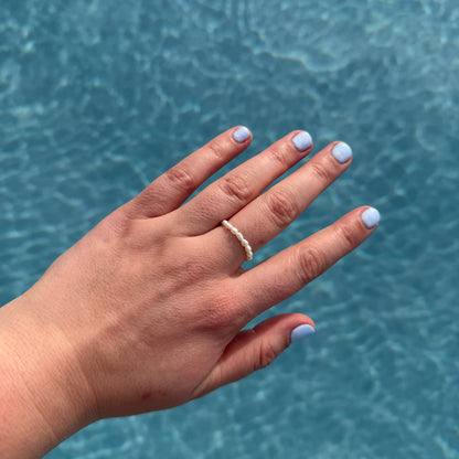 Hand with a ring against a blue water background
