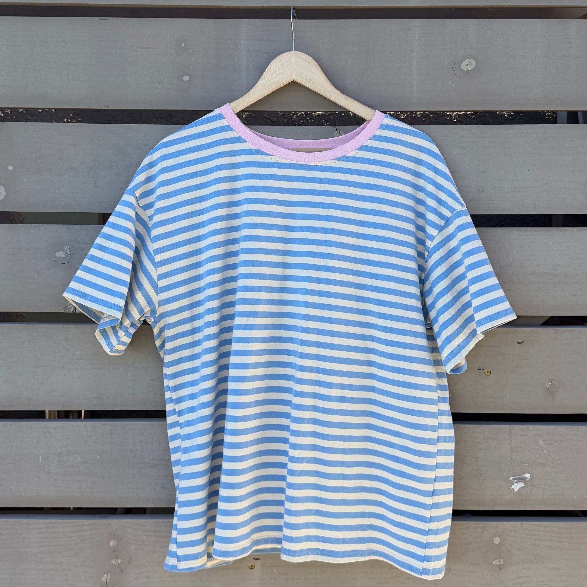 Blue and white striped shirt on a hanger against a wooden background
