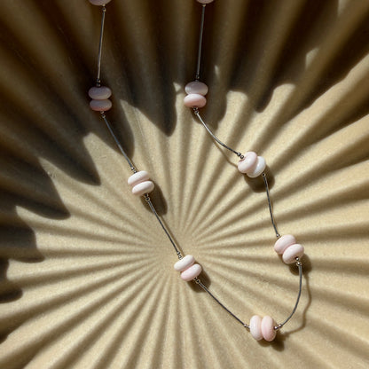 Necklace with pink beads on a textured beige background
