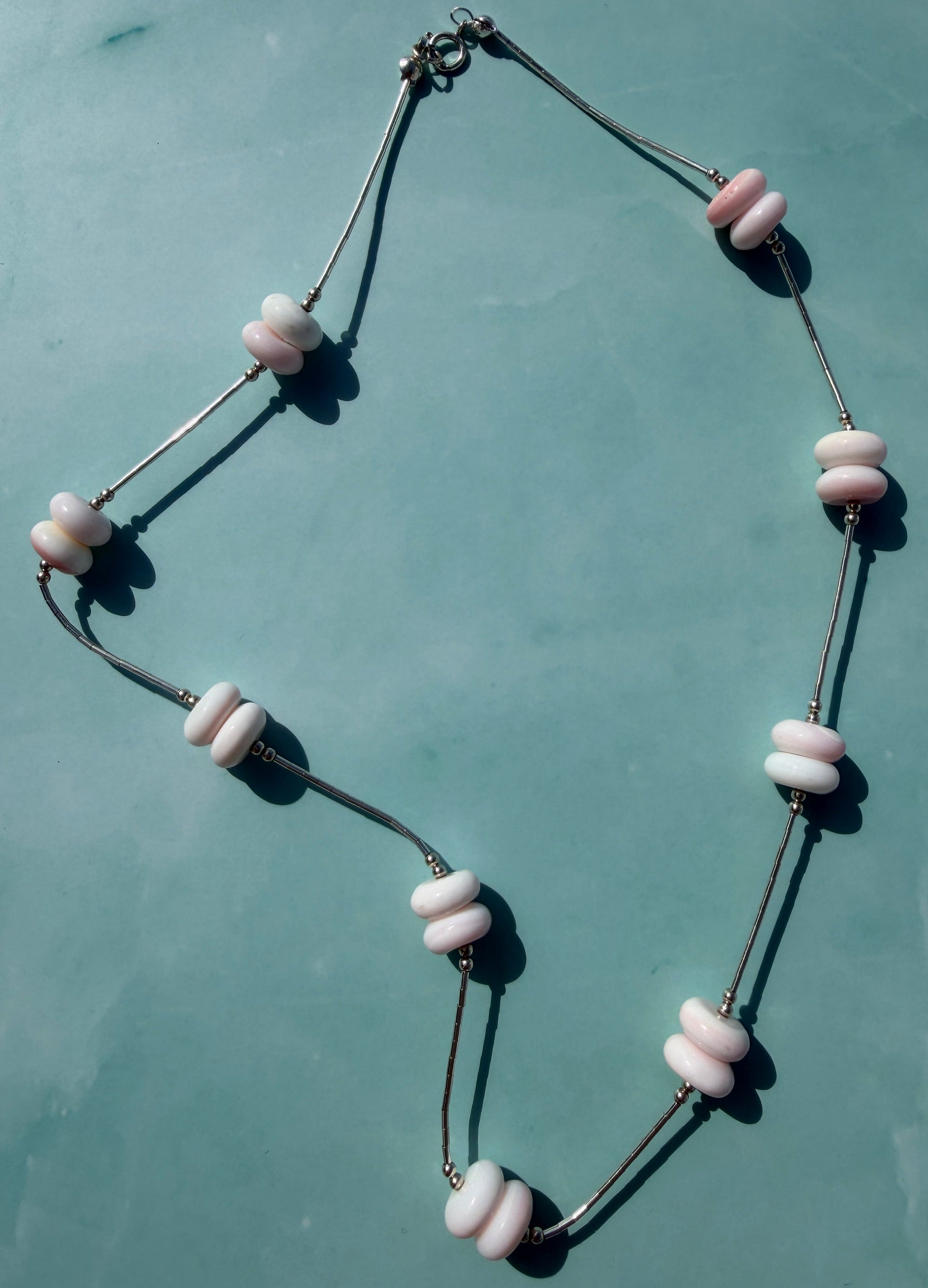 Necklace with pink and black beads on a light blue background