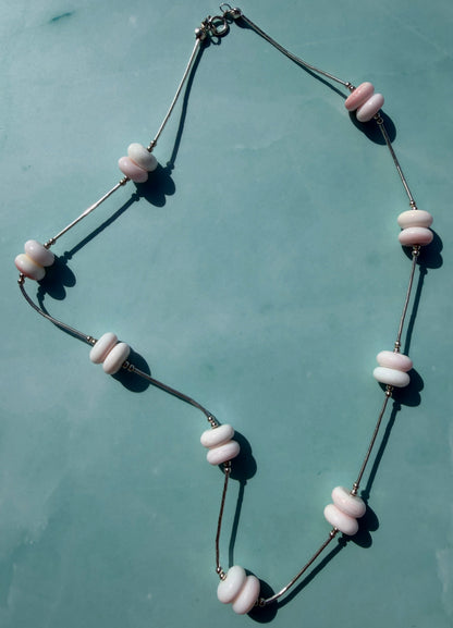 Necklace with pink and black beads on a light blue background