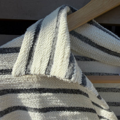 Close-up of a striped fabric with black and white pattern on a wooden surface.