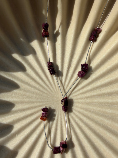Necklace with purple chips on a textured beige surface