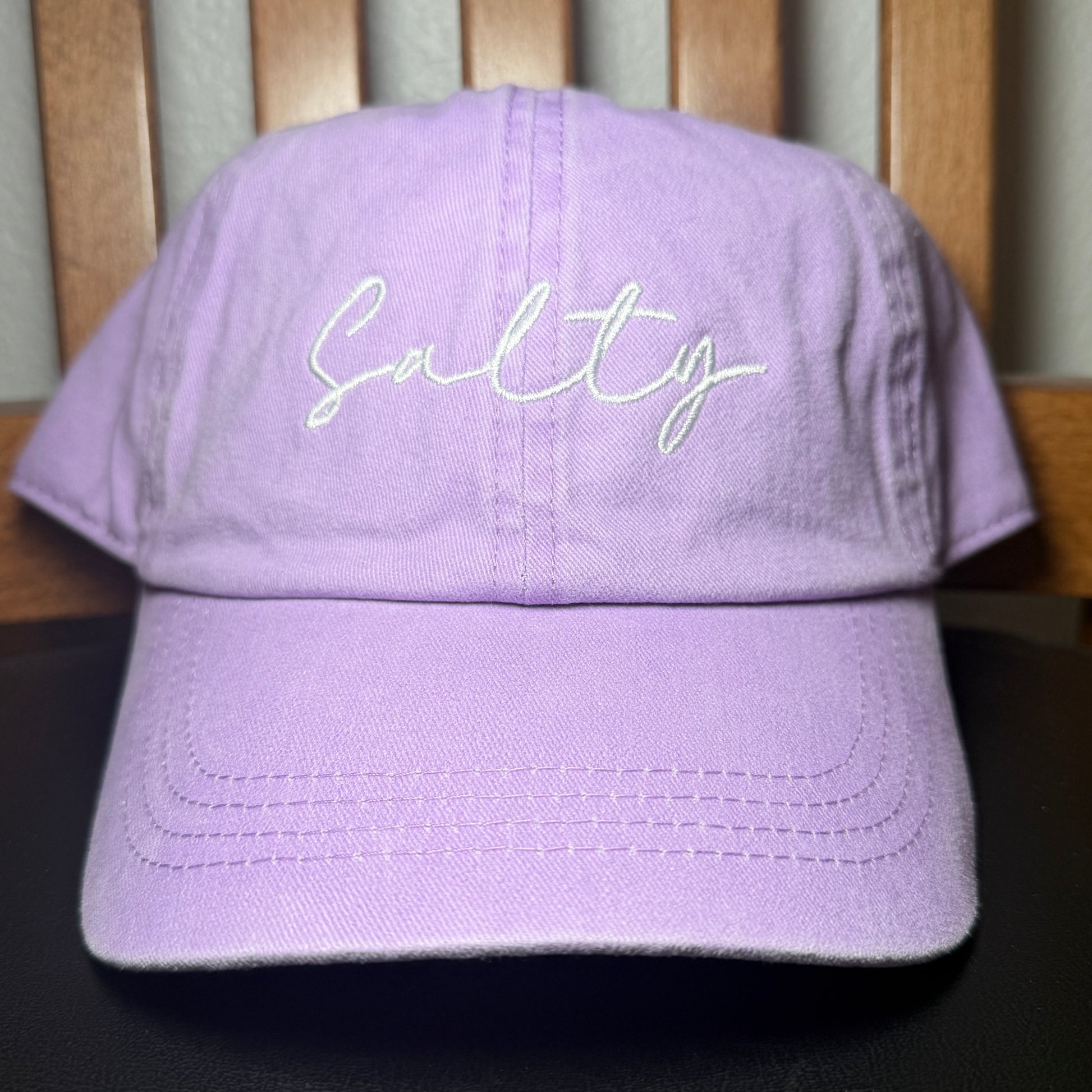 Purple baseball hat with 'Salty' embroidery on a wooden surface