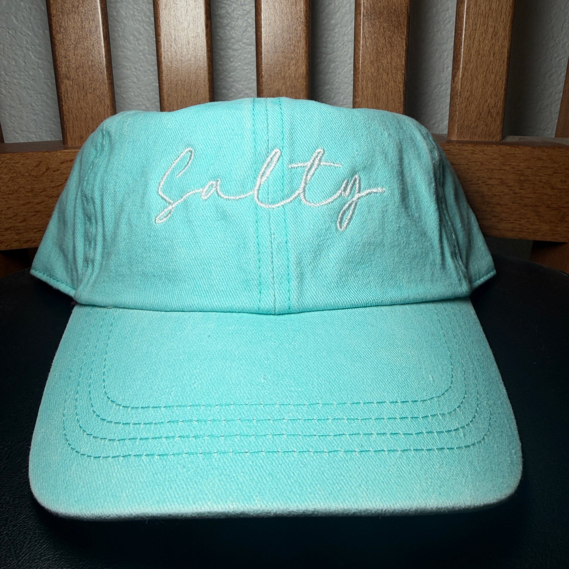 Light blue bucket hat with 'Salty' embroidery on a wooden surface