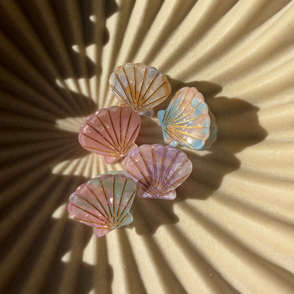 Colorful seashell earrings on a textured beige background