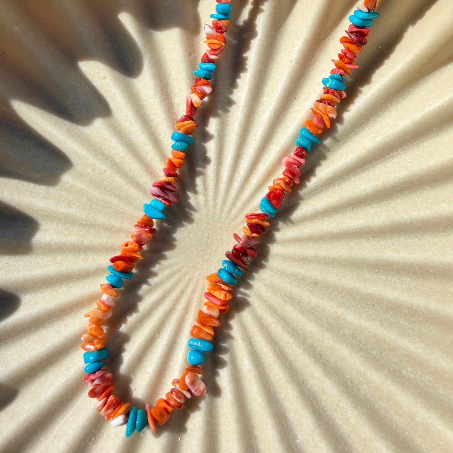 Colorful beaded necklace on a textured beige surface