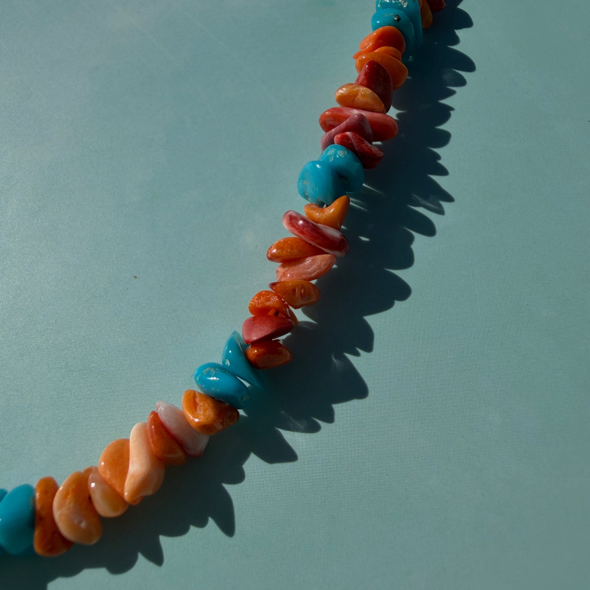 Colorful beaded necklace on a light blue background