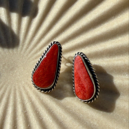 Pair of red earrings on a textured beige background