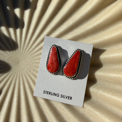 Card with red earrings on a textured beige background