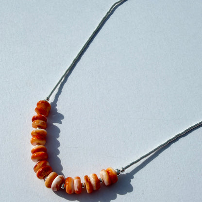 Necklace with orange beads on a light gray background