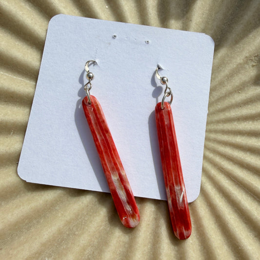 Red stone earrings on a white card with a sunburst patterned background
