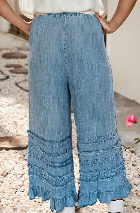 Denim wide-leg pants with ruffled bottom hem on a neutral background