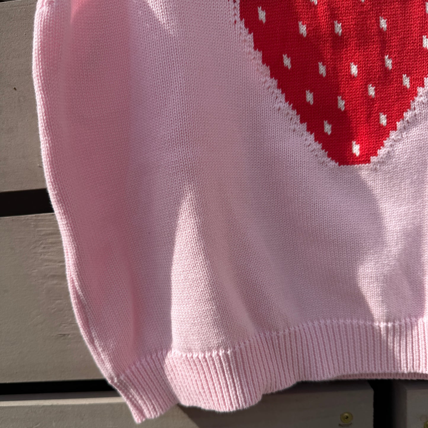 Pink fabric with a strawberry design on a wooden surface
