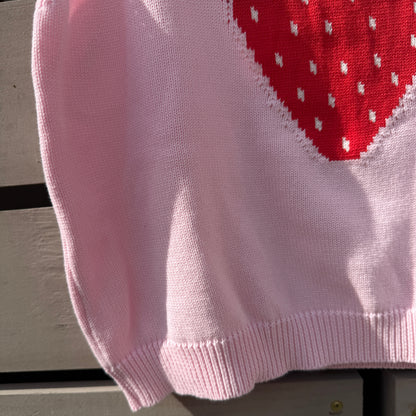 Pink fabric with a strawberry design on a wooden surface