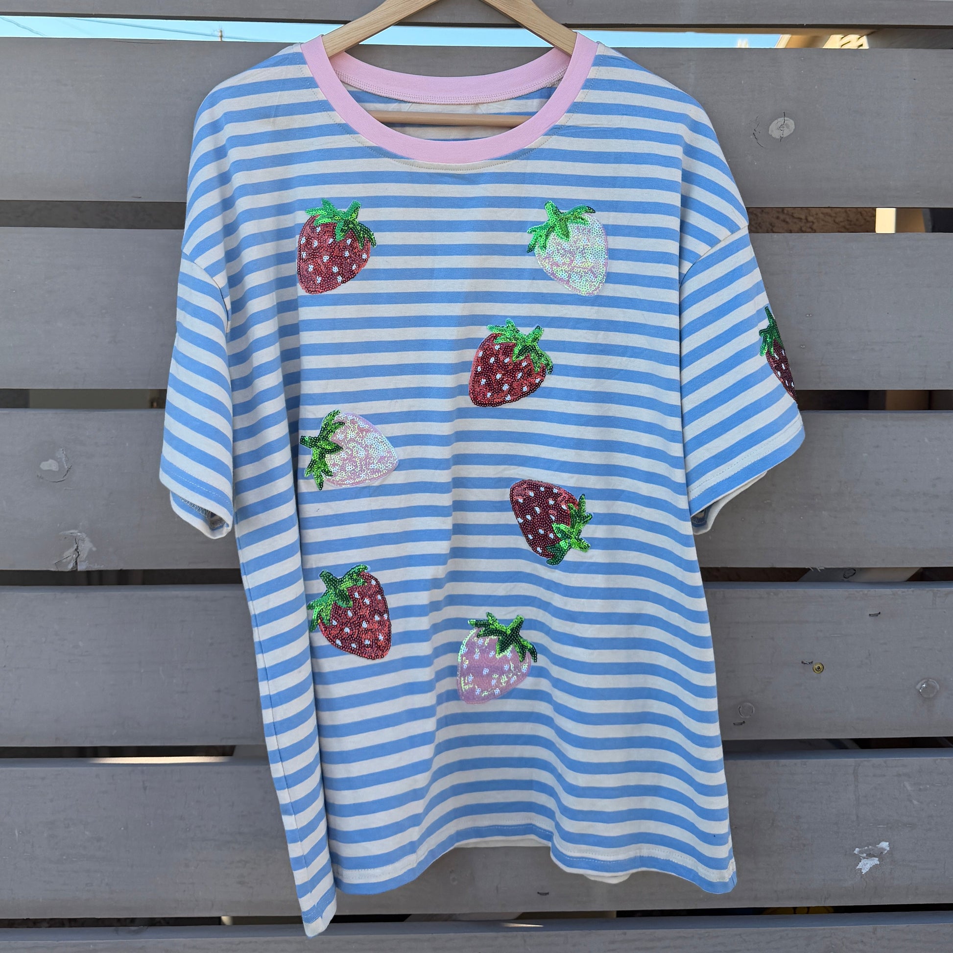 Blue and white striped t-shirt with strawberry designs on a wooden background