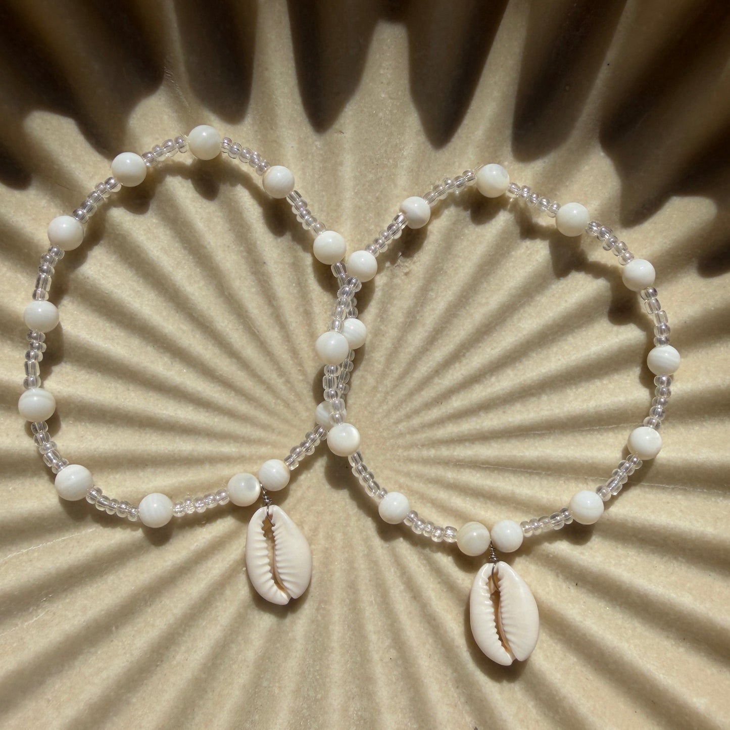 Beaded bracelet with cowrie shells on a textured beige background