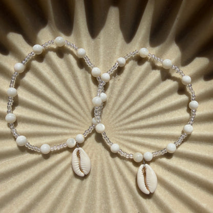 Beaded bracelet with cowrie shells on a textured beige background