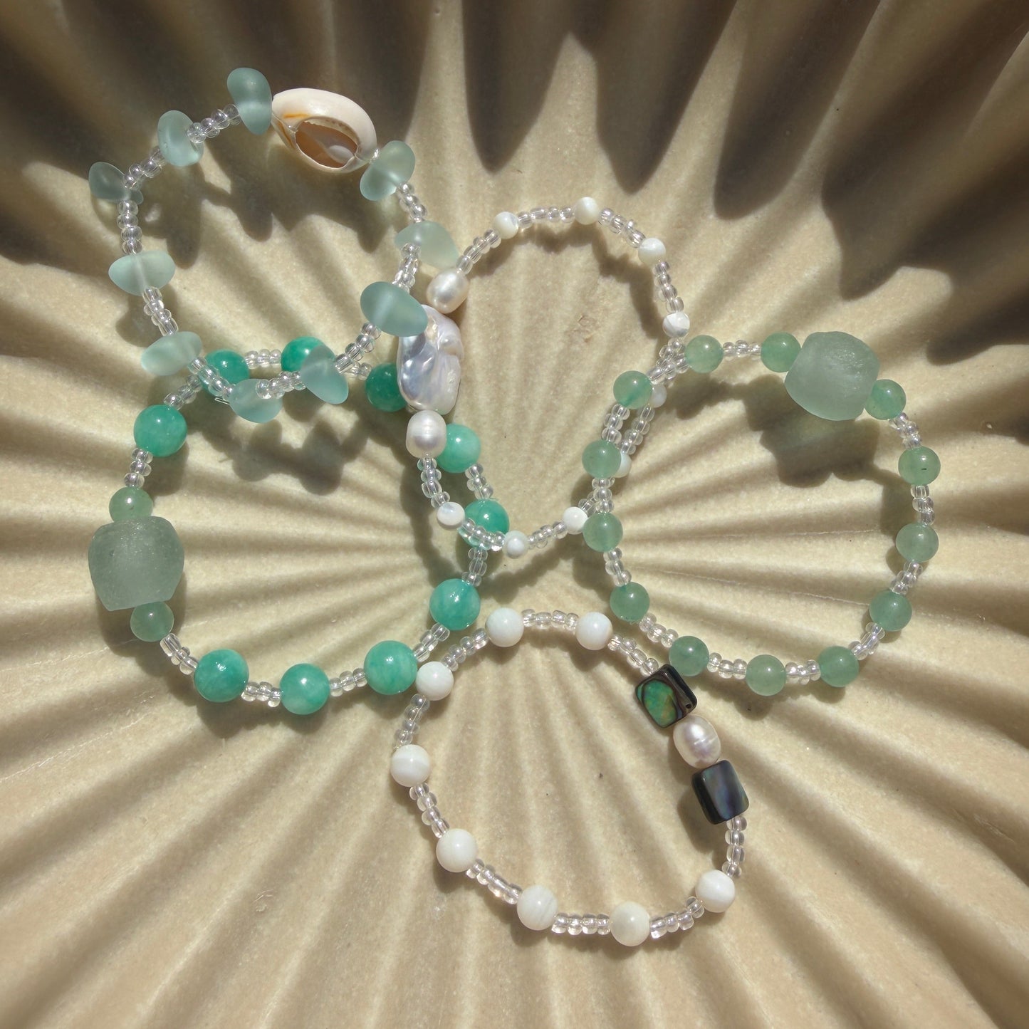 Two beaded bracelets on a textured beige surface