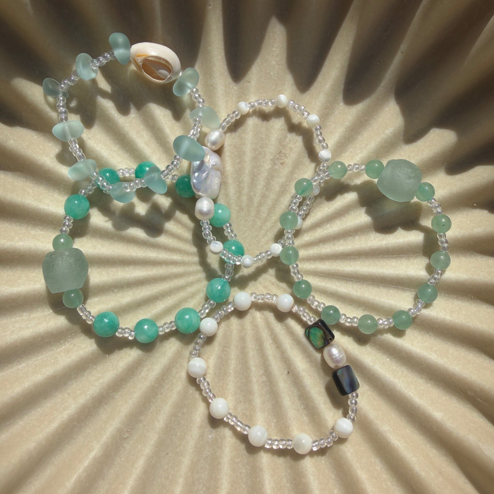 Two beaded bracelets on a textured beige surface
