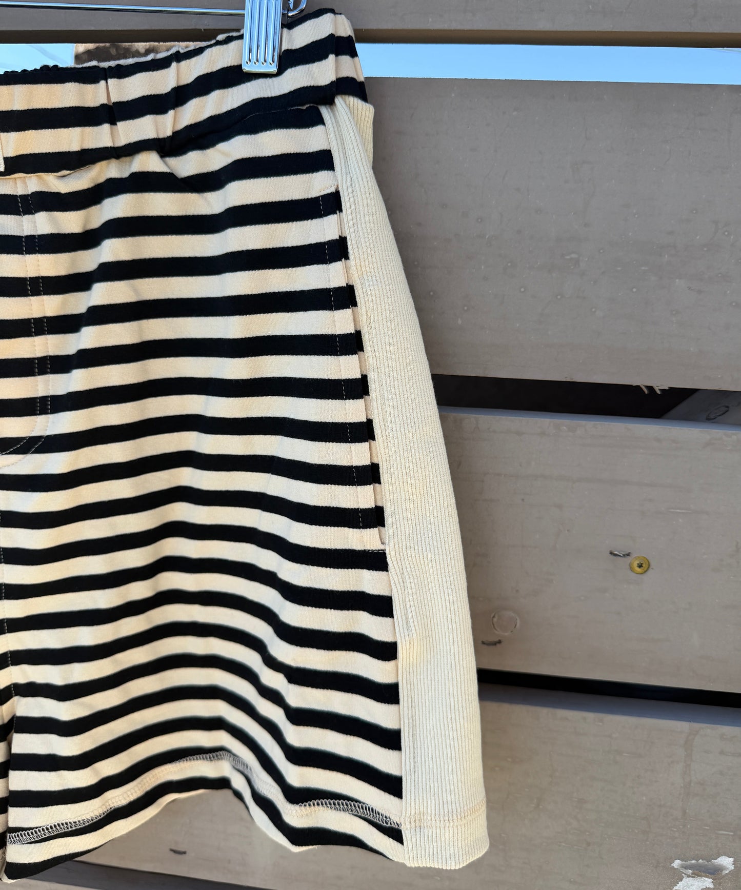 Black and white striped shorts on a clothesline against a concrete wall.