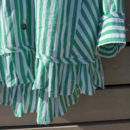 Green and white striped shirt with ruffled hem on a neutral background