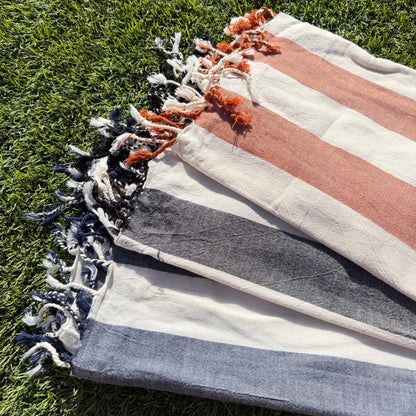 Striped towel with tassels on a grassy background