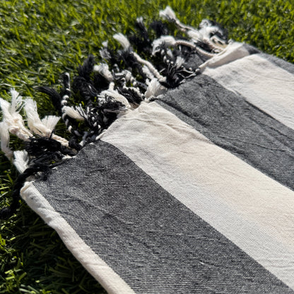 Striped towel with tassels on a grassy surface