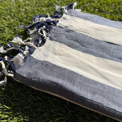 Striped towel with tassels on a grassy background