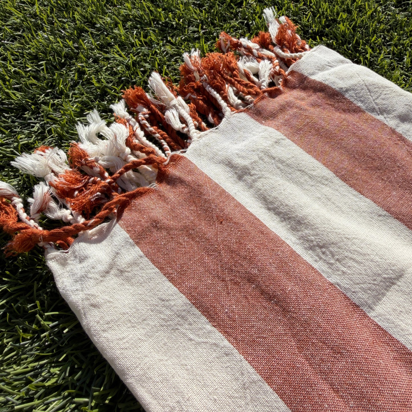 Striped towel with tassels on grass