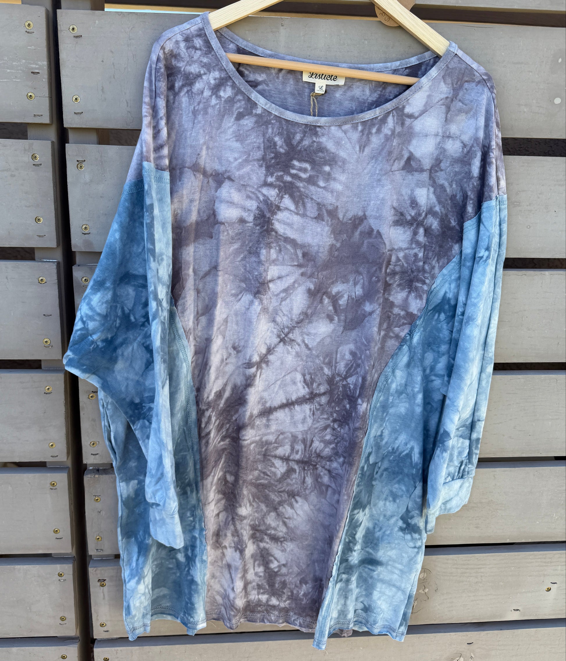 Tie-dye dress on a hanger against a wooden panel background