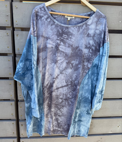 Tie-dye dress on a hanger against a wooden panel background