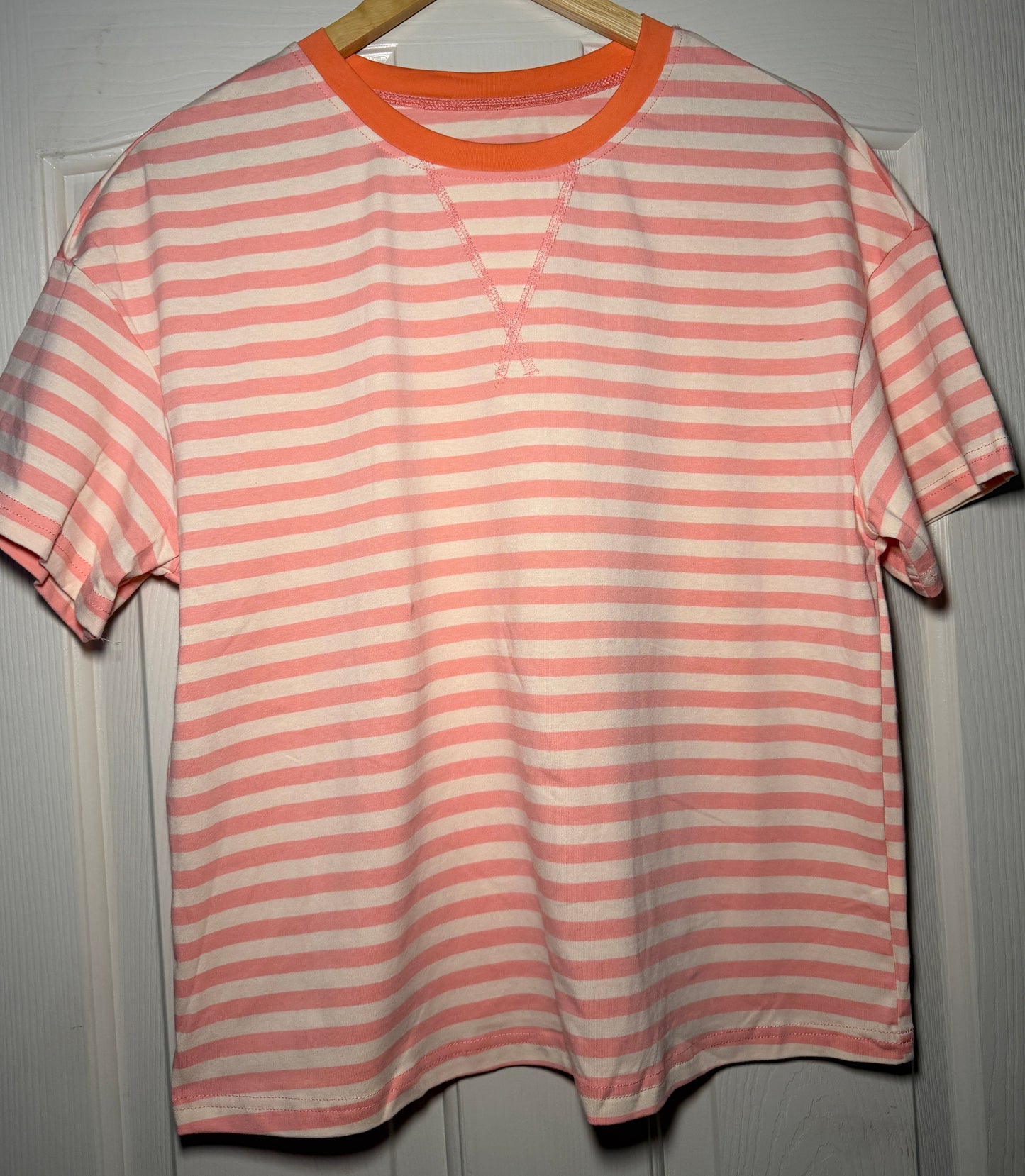 Pink and white striped shirt on a hanger against a gray background